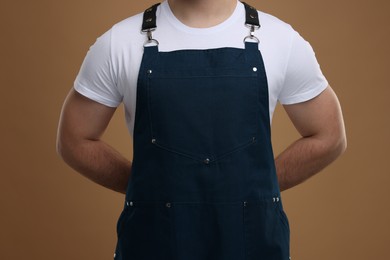Photo of Man in kitchen apron on brown background, closeup. Mockup for design