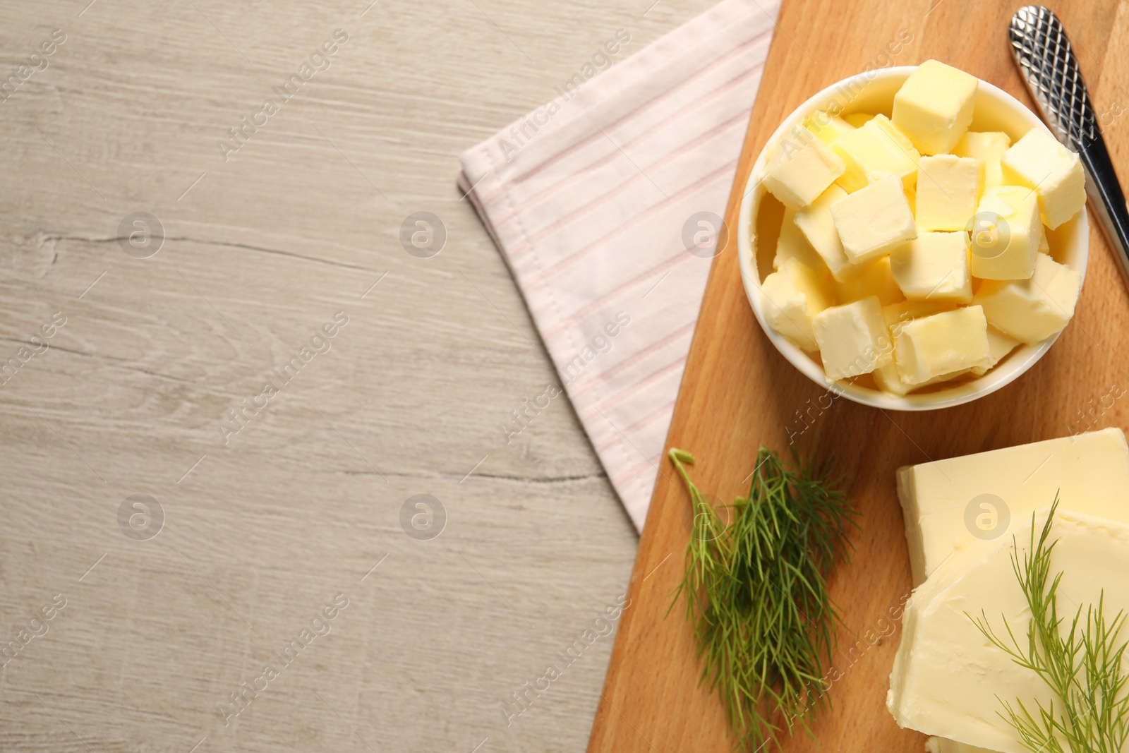 Photo of Tasty butter with dill and knife on wooden table, top view. Space for text