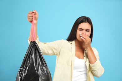 Photo of Woman holding full garbage bag on light blue background