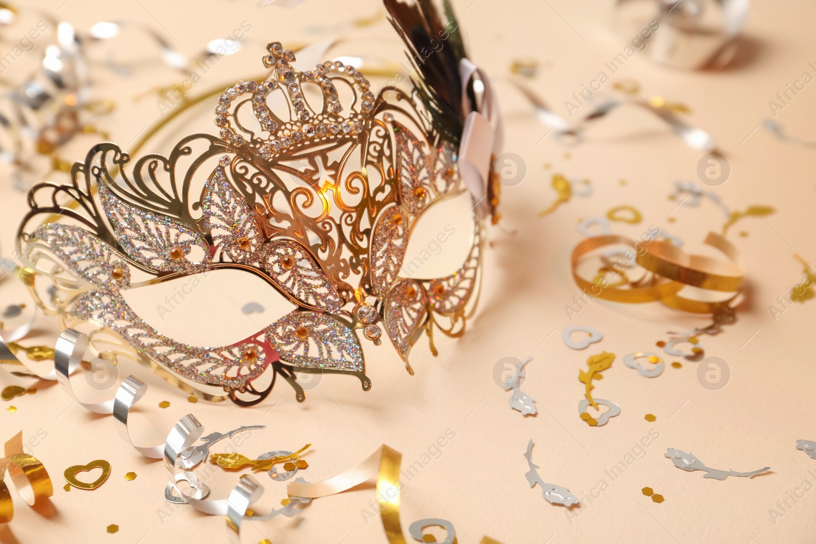 Photo of Beautiful carnival mask and party decor on beige background, closeup