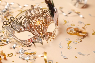 Photo of Beautiful carnival mask and party decor on beige background, closeup
