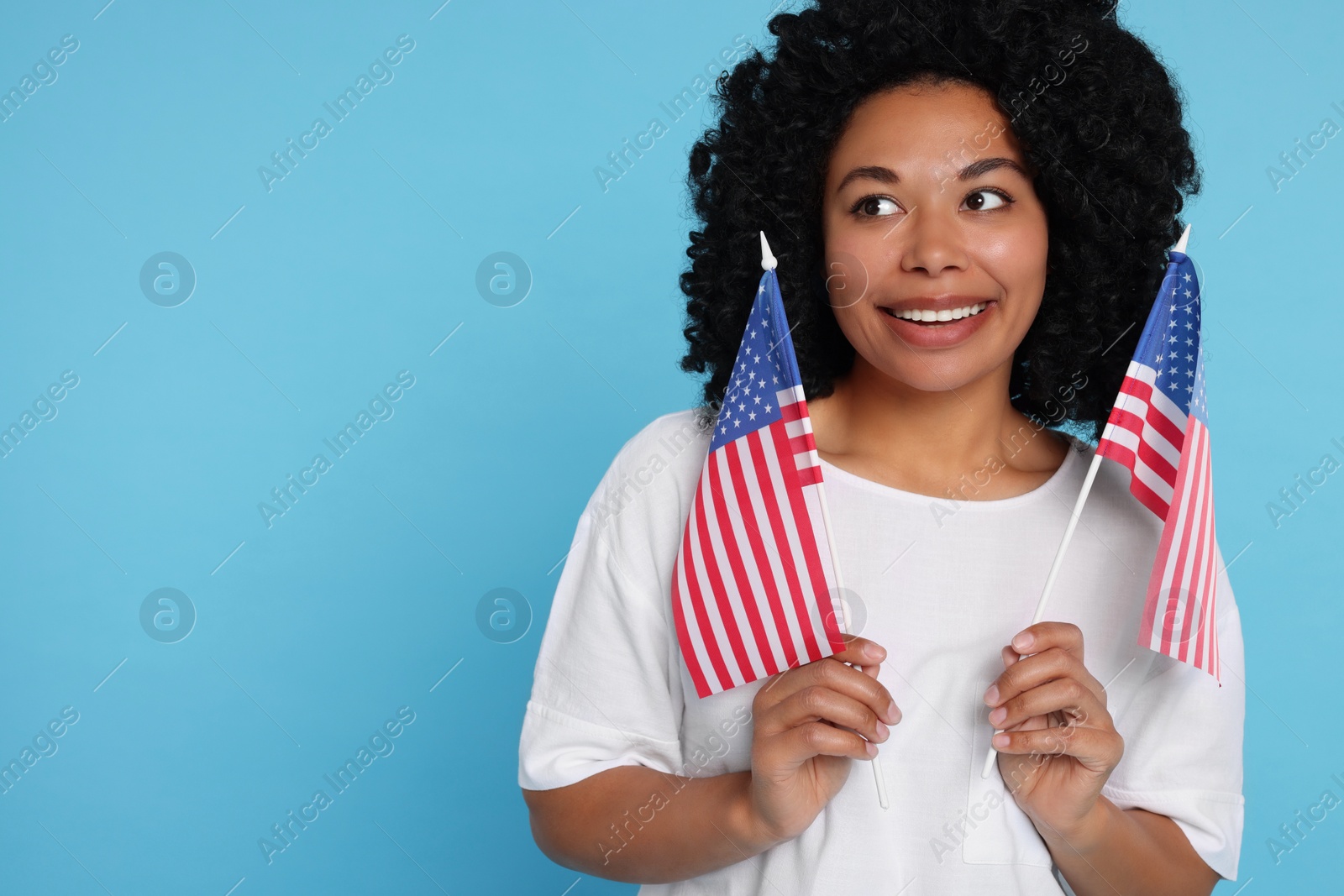 Photo of 4th of July - Independence Day of USA. Happy woman with American flags on light blue background, space for text