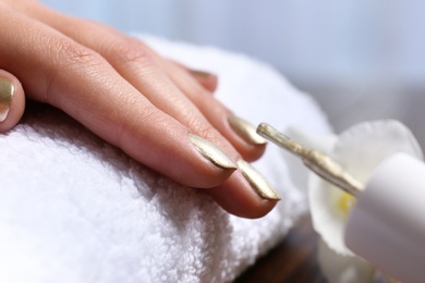 Photo of Woman getting manicure in salon, closeup. Nail polish trends