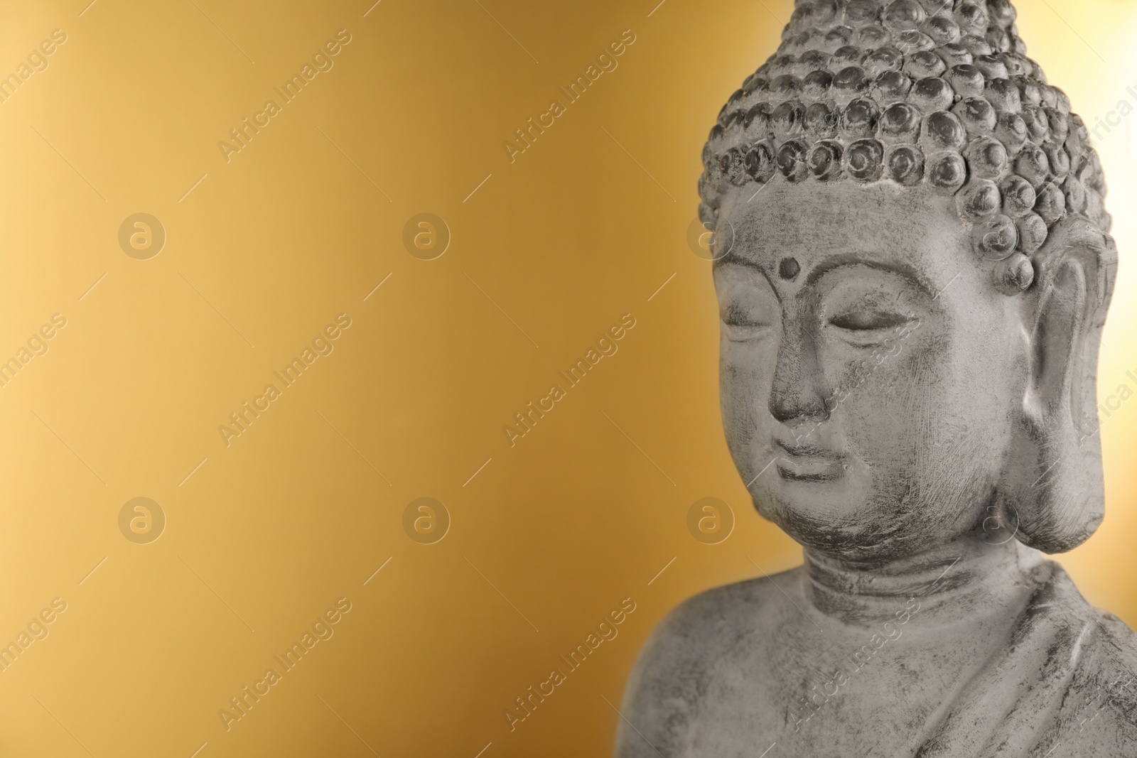 Photo of Buddha statue on golden background, closeup. Space for text