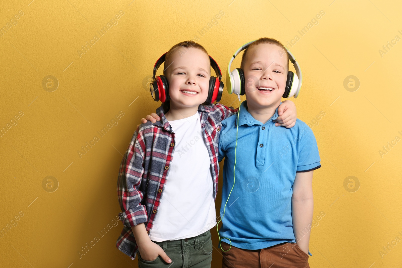 Photo of Portrait of cute twin brothers with headphones on color background