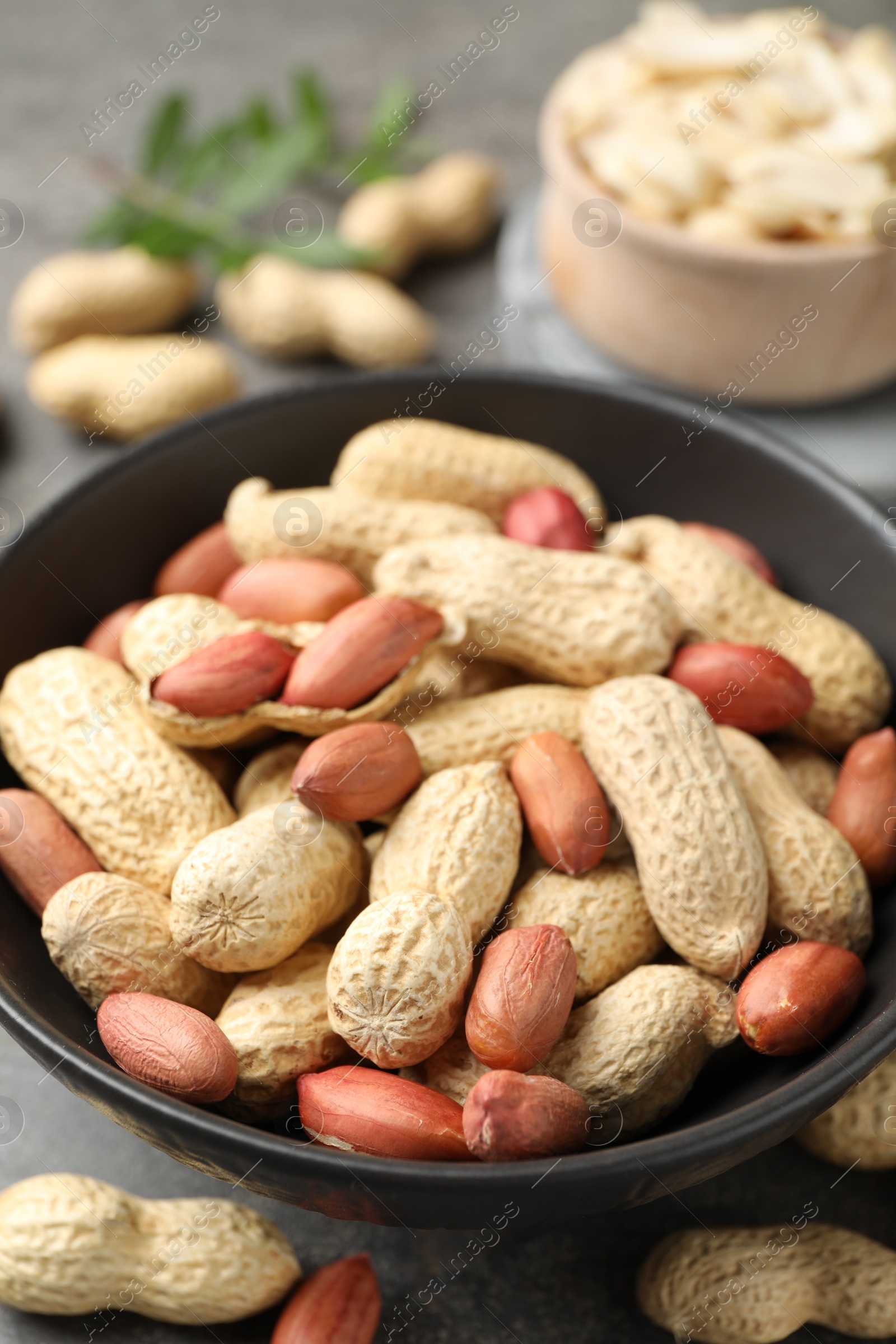 Photo of Fresh unpeeled peanuts in bowl on grey table