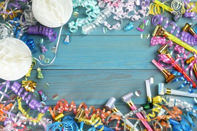 Photo of Frame of colorful serpentine streamers and other party accessories on light blue wooden background, flat lay. Space for text