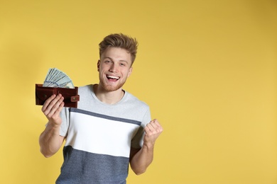 Photo of Young man with money in wallet on color background. Space for text