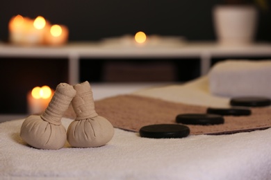 Photo of Herbal compresses and stones on massage table in spa salon. Space for text