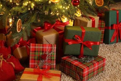 Many gift boxes under Christmas tree in room