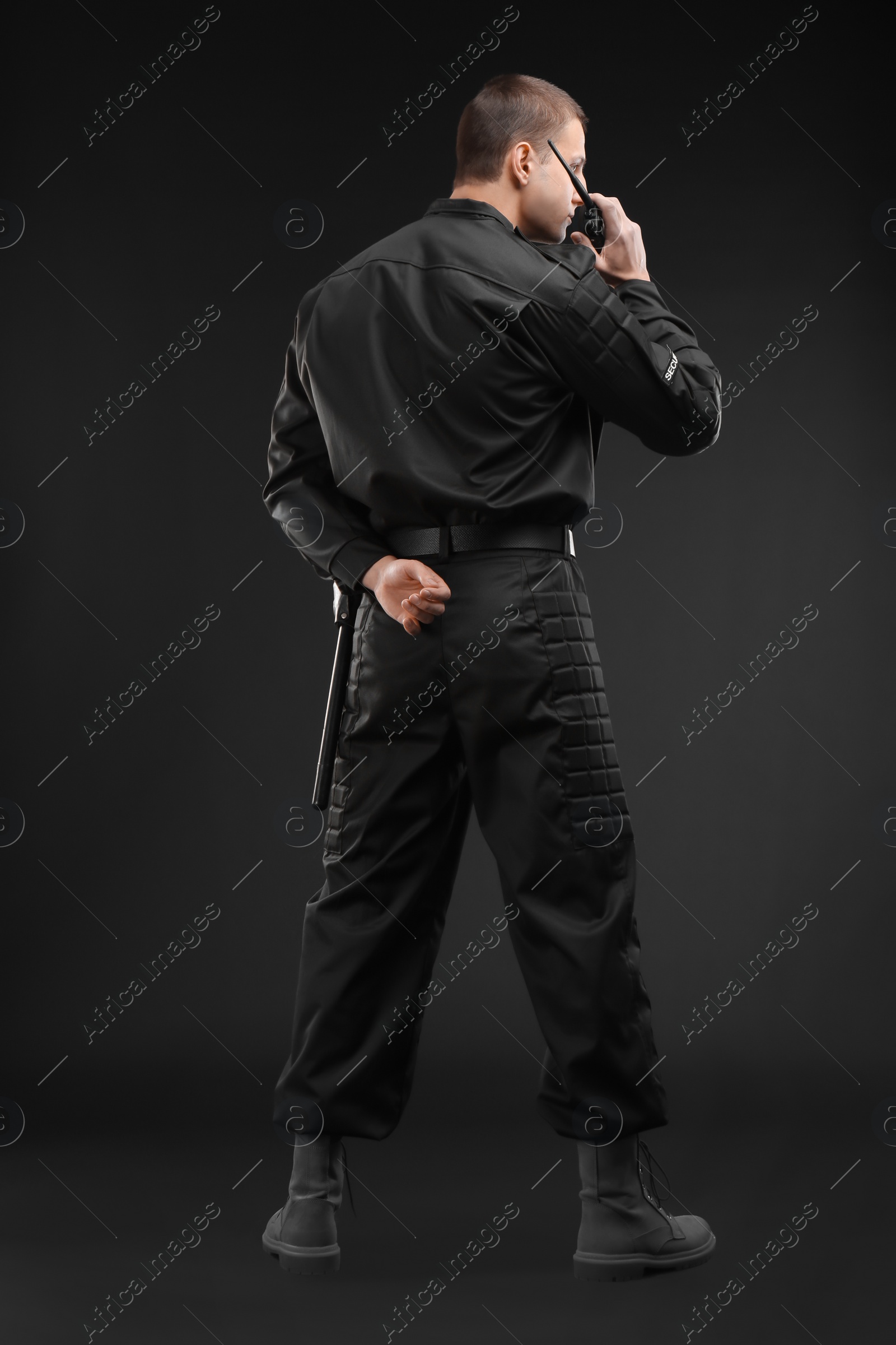 Photo of Male security guard using portable radio transmitter on dark background