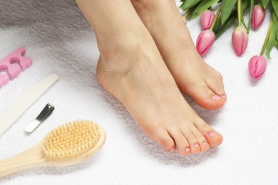 Photo of Woman with neat toenails after pedicure procedure on white terry towel, closeup
