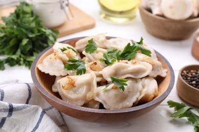 Photo of Delicious dumplings (varenyky) with potatoes, onion and parsley served on white wooden table