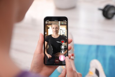 Image of Woman having workout with personal trainer via smartphone at home, closeup