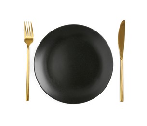 Photo of Clean plate and golden cutlery on white background, top view