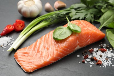 Photo of Fresh salmon and ingredients for marinade on black table, closeup