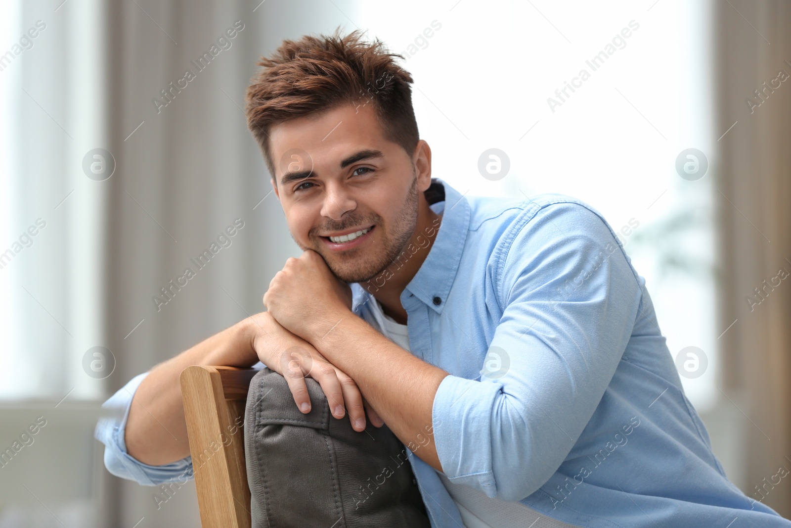 Photo of Portrait of handsome young man sitting on chair in room