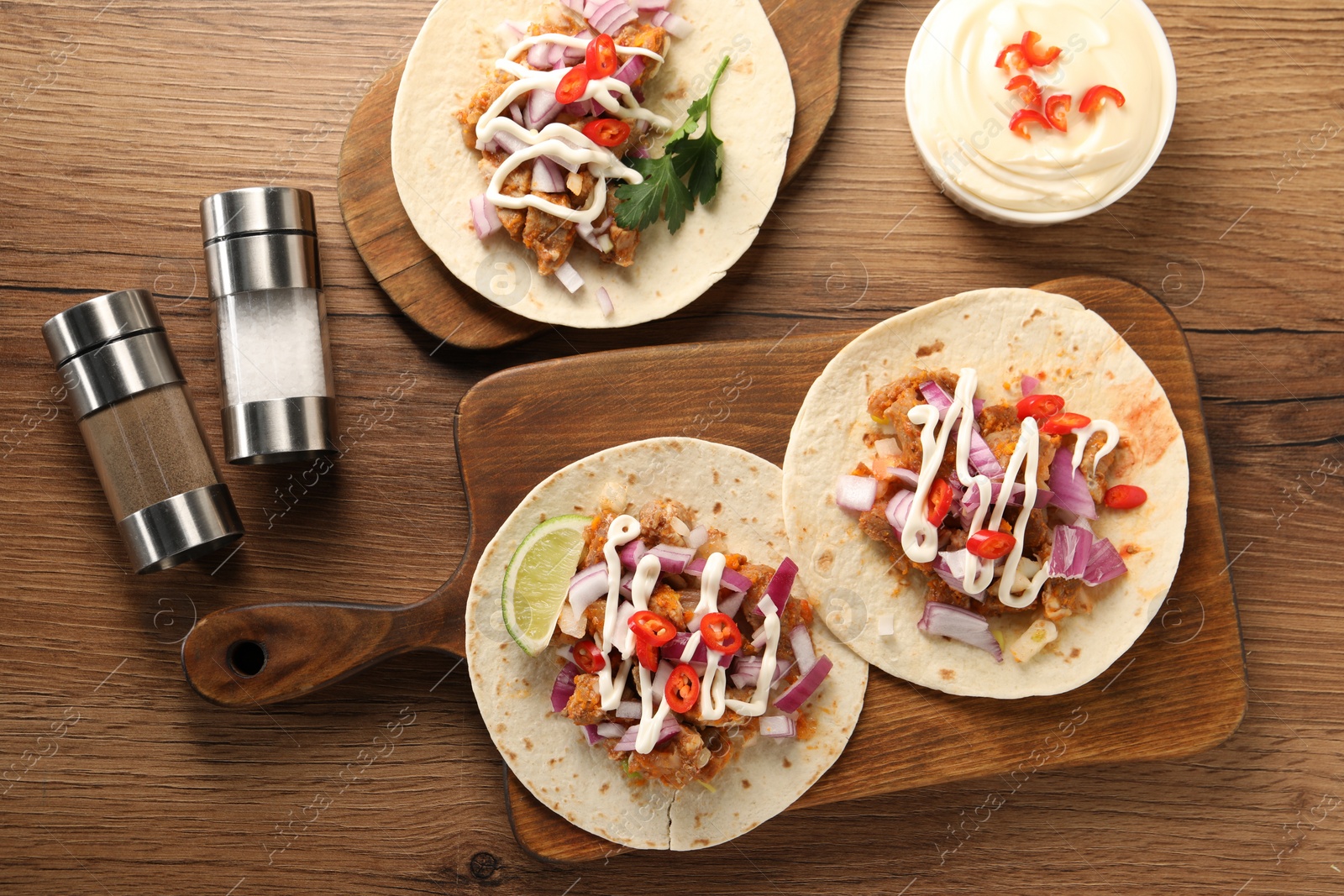 Photo of Delicious tacos with vegetables, meat and sauce on wooden table, flat lay