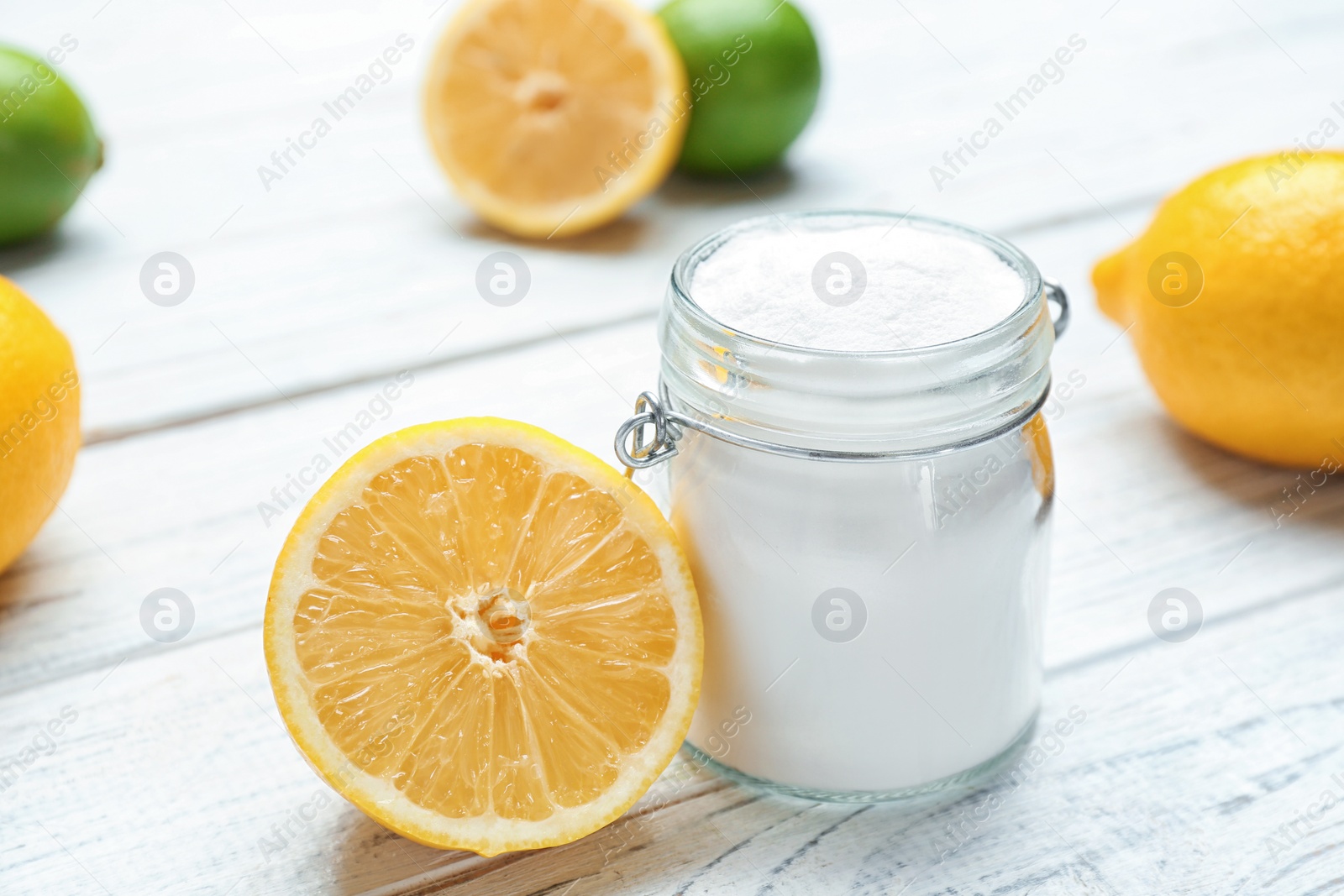 Photo of Jar with baking soda and lemon on white wooden table