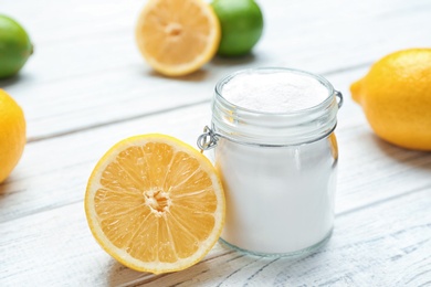 Photo of Jar with baking soda and lemon on white wooden table