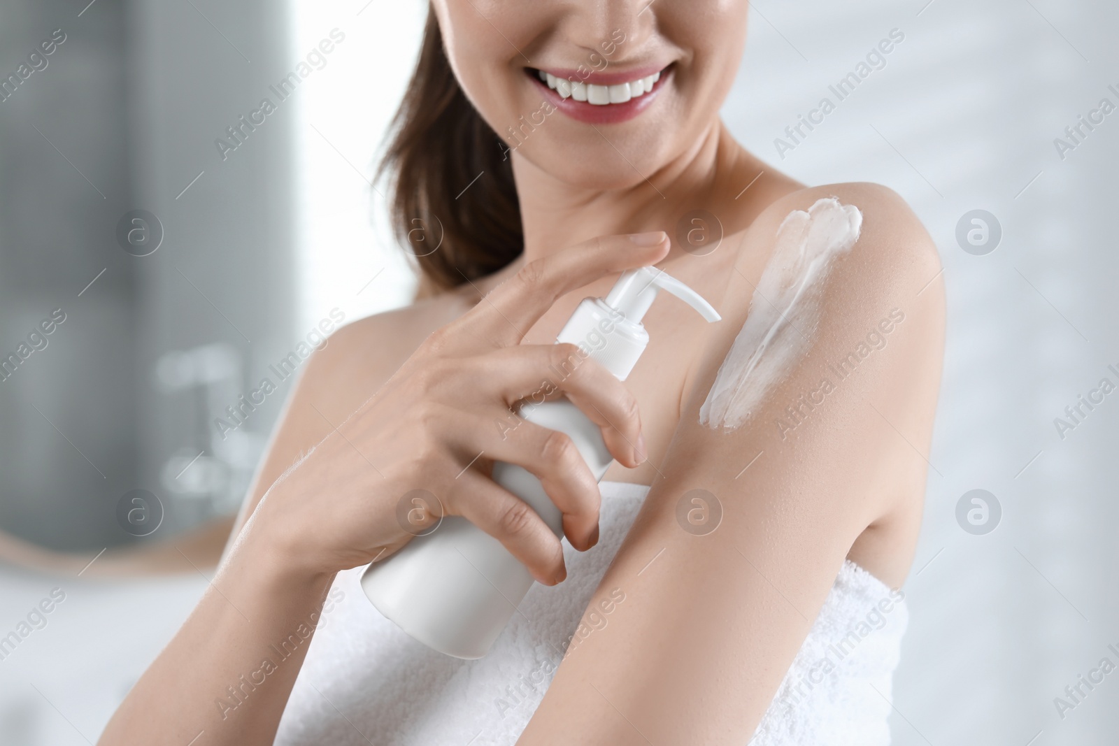 Photo of Woman applying body cream onto arm in bathroom, closeup