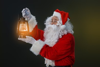 Photo of Merry Christmas. Santa Claus with vintage lantern on dark background