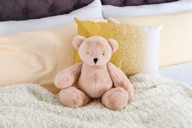 Photo of Cute teddy bear sitting on bed indoors