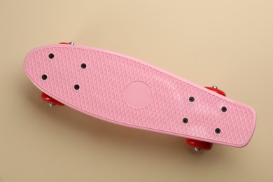 Pink skateboard on beige background, top view