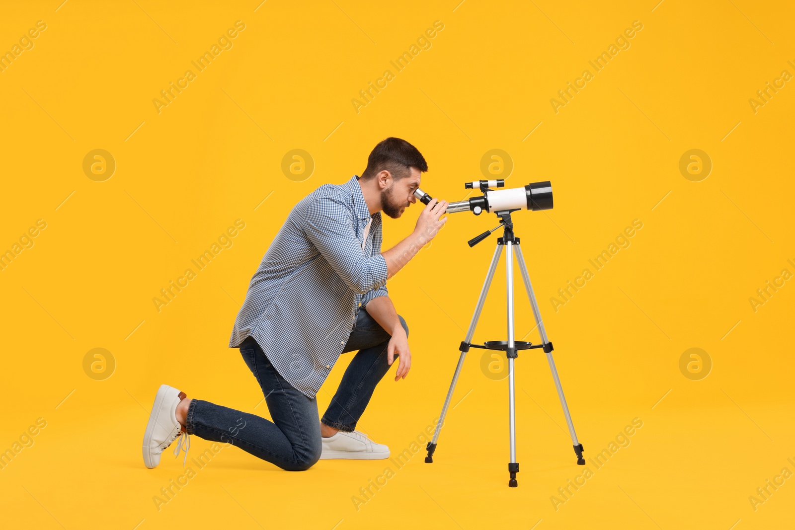 Photo of Astronomer looking at stars through telescope on orange background