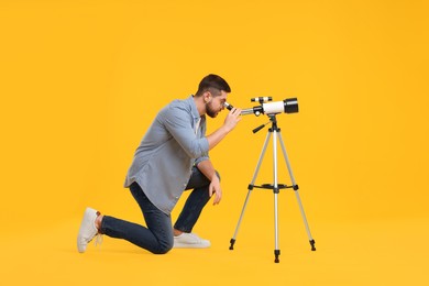 Astronomer looking at stars through telescope on orange background