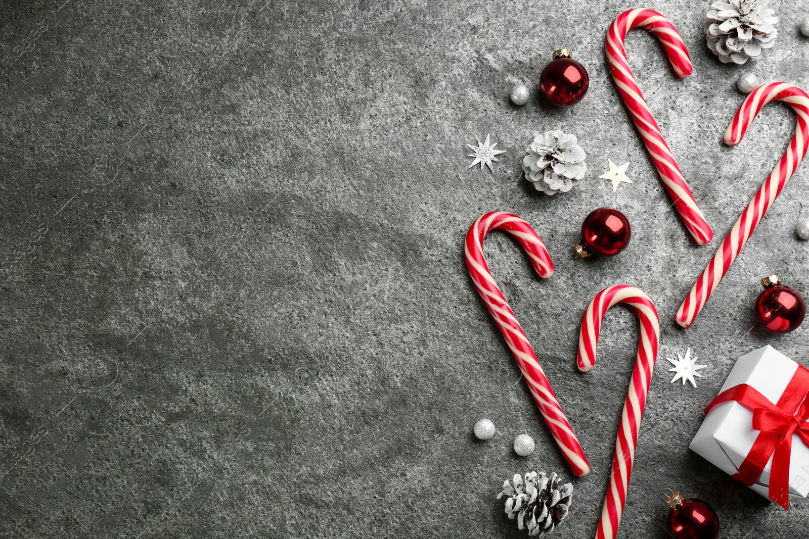Photo of Flat lay composition with candy canes and Christmas decor on grey table. Space for text