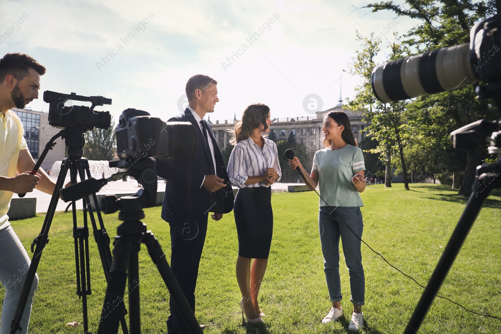 Photo of Professional journalist and operator with video camera taking interview outdoors