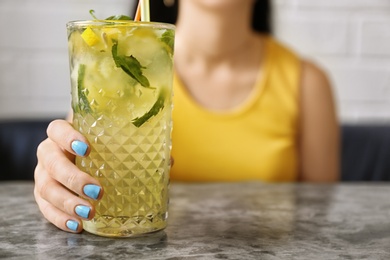 Photo of Woman with glass of lemonade at table, closeup