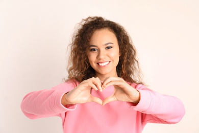 African-American woman making heart with her hands on white background