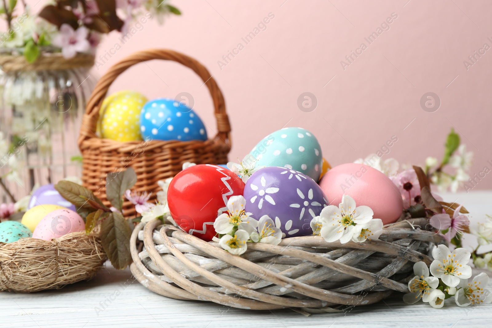 Photo of Composition with painted Easter eggs and flowers on table