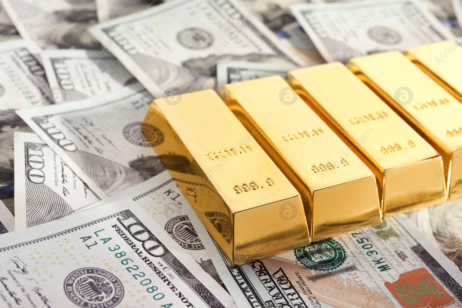 Photo of Shiny gold bars on pile of dollar bills