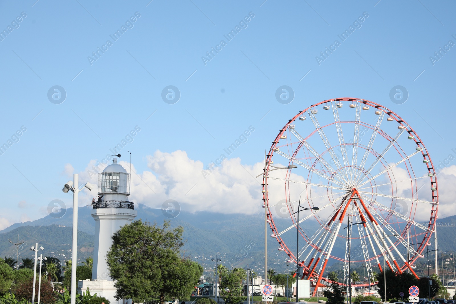 Photo of Batumi, Georgia - October 12, 2022: Ferris wheel and lighthouse in city near mountains