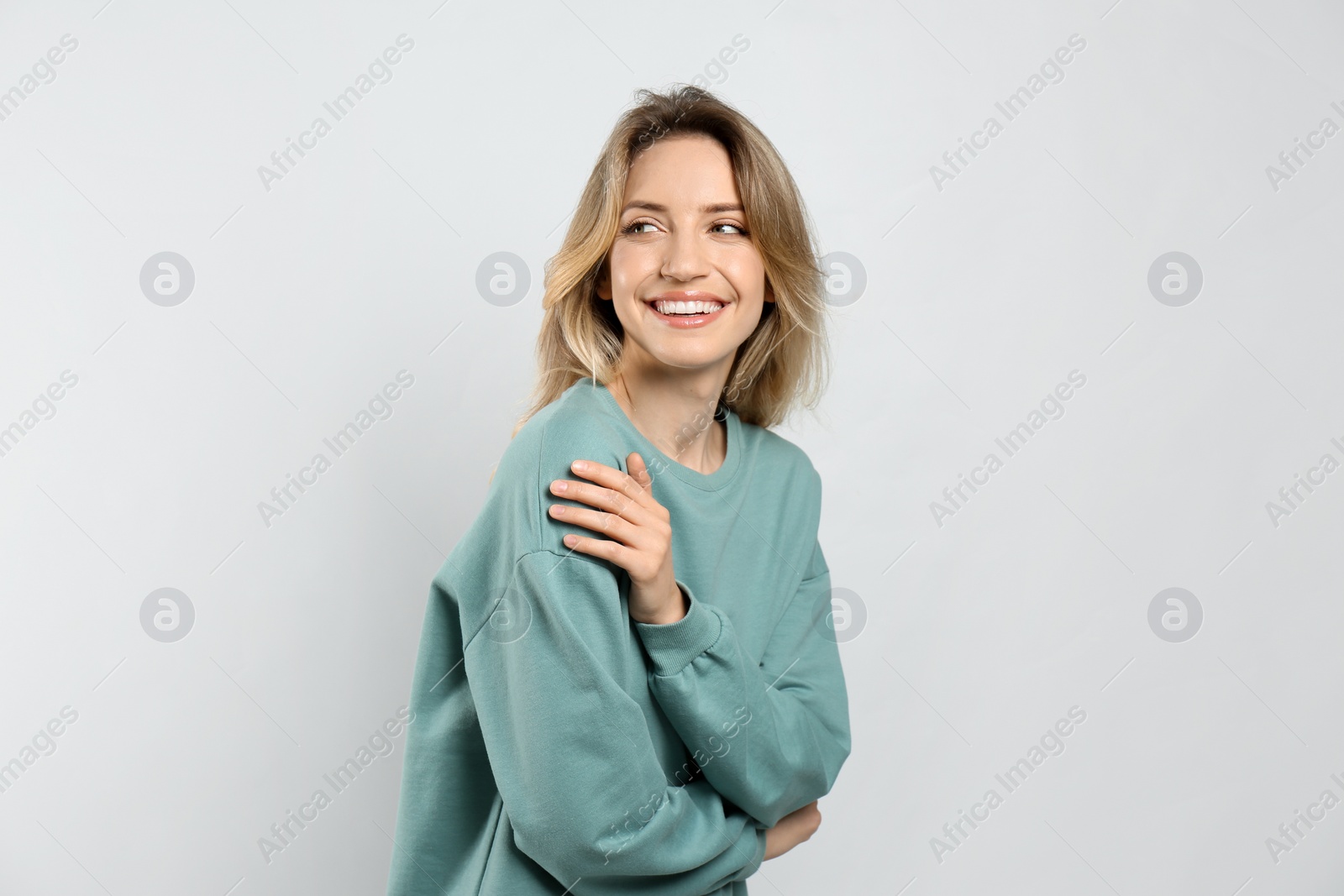 Photo of Portrait of happy young woman with beautiful blonde hair and charming smile on light background