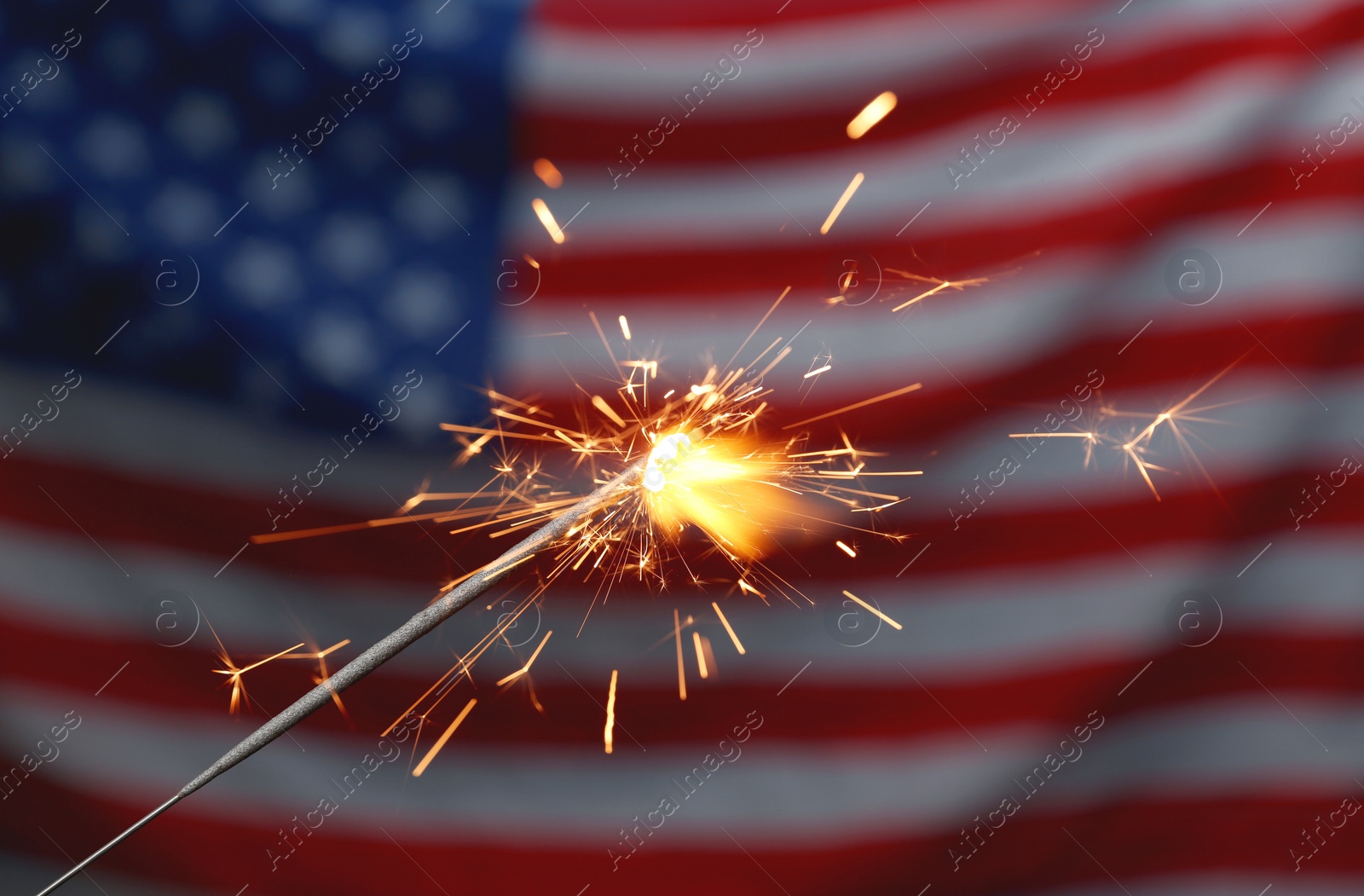 Photo of Burning sparkler against USA flag, closeup. Happy Independence Day