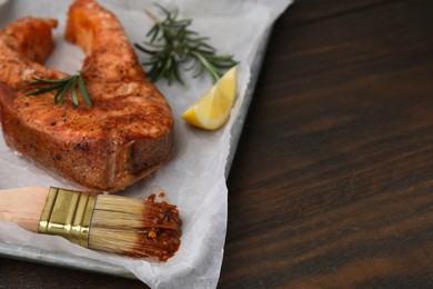 Photo of Fresh marinade, fish, brush and other products on wooden table, closeup. Space for text