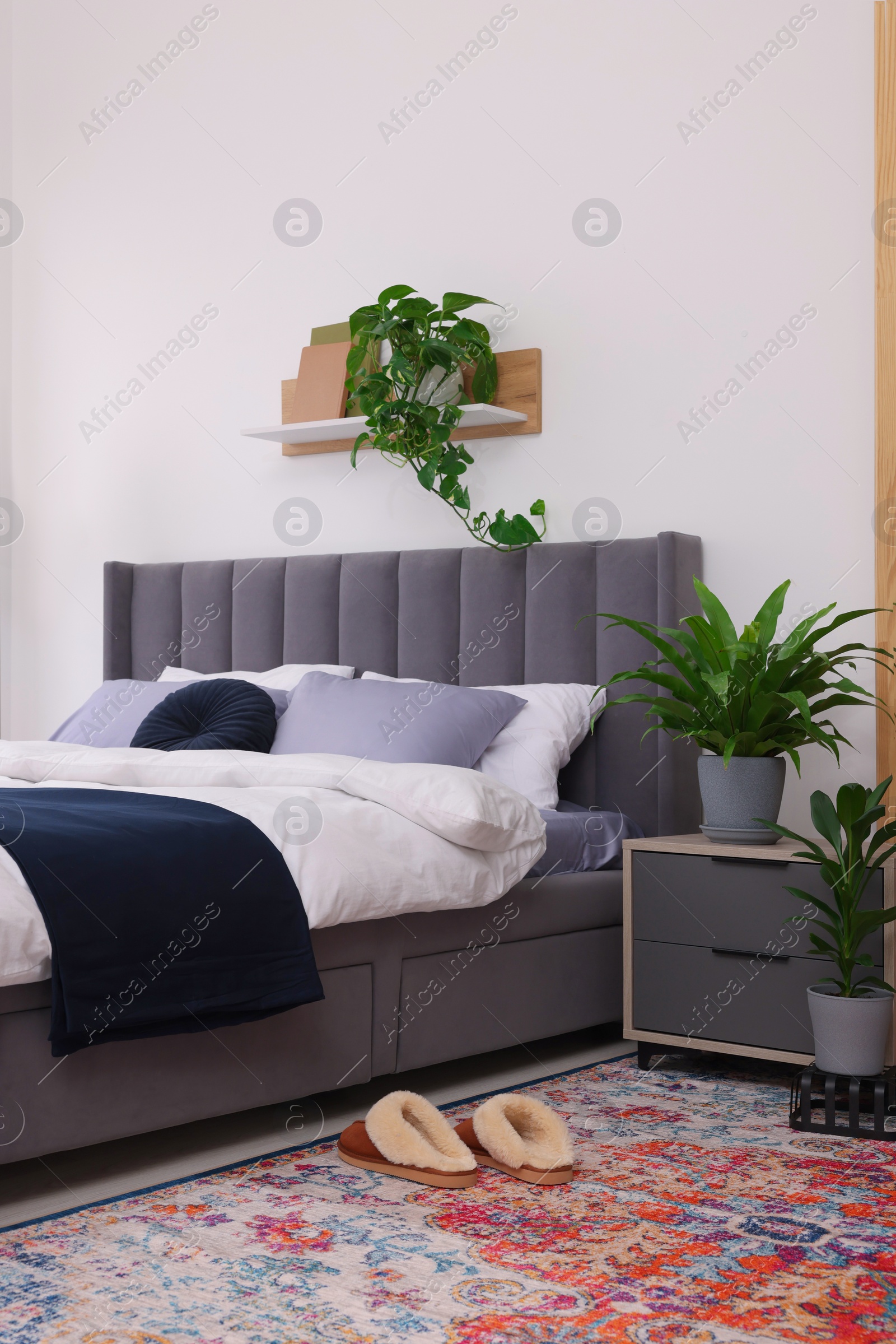 Photo of Beautiful green houseplants and bed in room. Bedroom interior