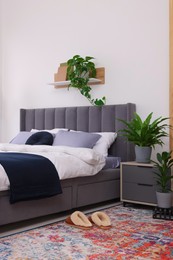 Beautiful green houseplants and bed in room. Bedroom interior