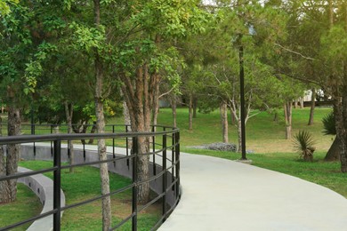 Photo of Picturesque view of bridge with metal railing and many trees in park