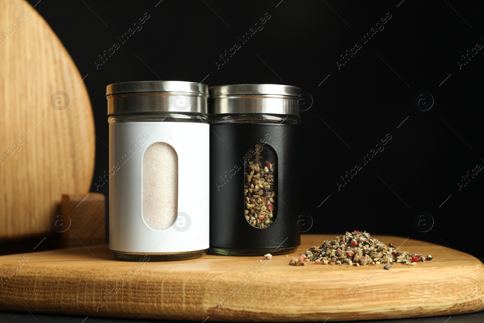 Photo of Salt and pepper shakers on table against black background. Space for text