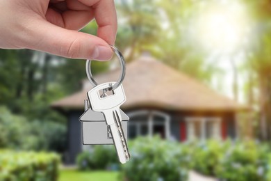 Woman holding key near house outdoors, closeup