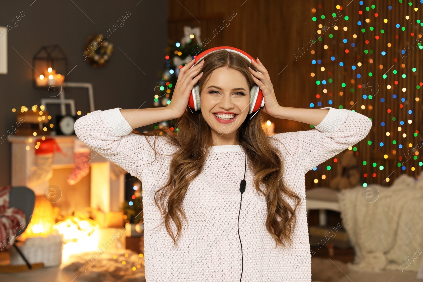 Photo of Happy young woman listening to Christmas music at home