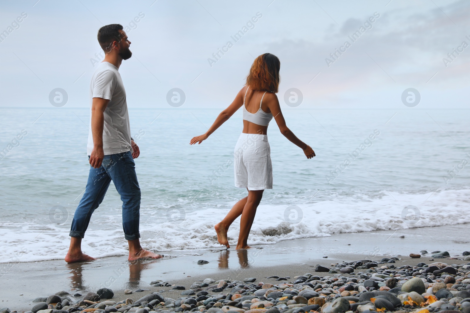 Photo of Happy young couple spending time together on beach near sea