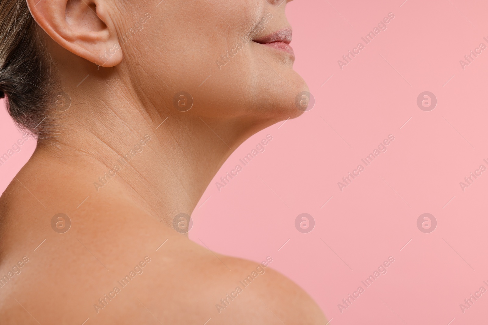 Photo of Mature woman with healthy skin on pink background, closeup. Space for text