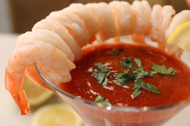 Photo of Tasty shrimp cocktail with sauce in glass on blurred background, closeup