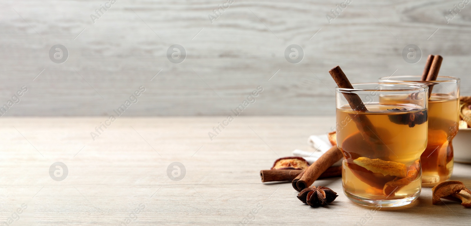 Photo of Delicious compote with dried apple slices, anise and cinnamon on white wooden table, space for text